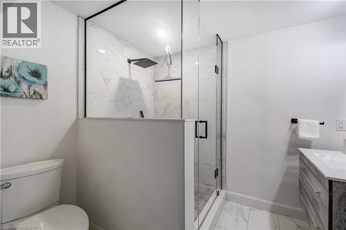 Modern bathroom featuring a glass-enclosed shower with black trim, a square matte black showerhead, and a half-wall partition - 29 Wiltshire Place, Ancaster, ON - Indoor Photo Showing Bathroom