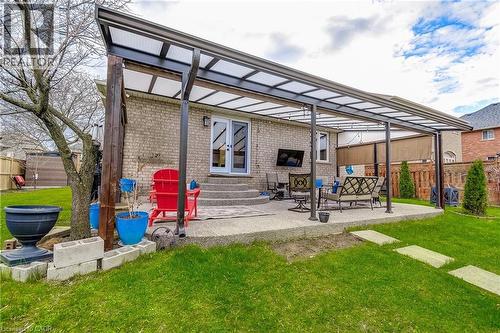 Expansive covered patio featuring a concrete surface, direct access via double doors, a brick exterior, and a manicured lawn with stepping stones - 29 Wiltshire Place, Ancaster, ON - Outdoor
