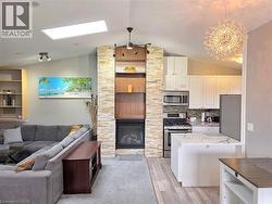 Open-concept living space featuring a stacked stone fireplace with built-in shelving, vaulted ceilings, and a skylight - 