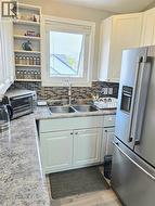 Kitchen featuring white cabinetry and a mosaic tile backsplash - 