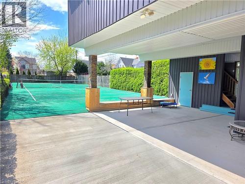 Large covered patio, outdoor tennis court with green surface and perimeter netting - 16 Forest Hill Road, St. Catharines, ON - Outdoor