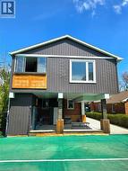 Contemporary exterior featuring vertical panel siding, a covered patio, balcony and court netting - 