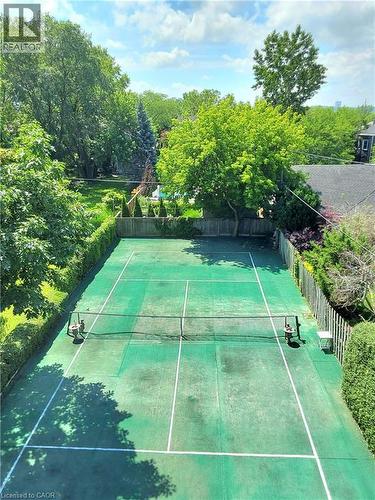 Roof view of full-size tennis court featuring a green turf playing surface with white line markings and perimeter fencing - 16 Forest Hill Road, St. Catharines, ON - Outdoor With Backyard