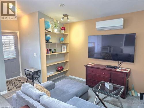 Living area featuring vinyl flooring, built-in shelving, lots of lighting and a wall-mounted air conditioning unit - 16 Forest Hill Road, St. Catharines, ON - Indoor