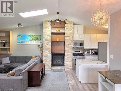 Open-concept living space featuring a stacked stone fireplace with built-in shelving, vaulted ceilings, and a skylight - 16 Forest Hill Road, St. Catharines, ON - Indoor With Fireplace