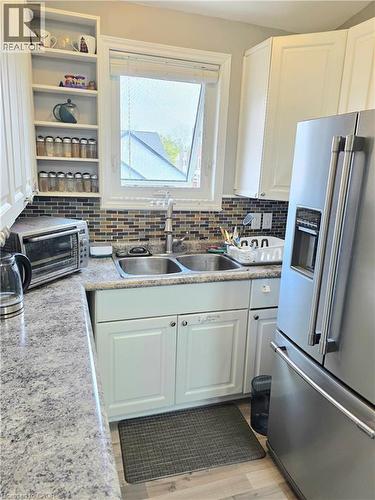 Kitchen featuring white cabinetry and a mosaic tile backsplash - 16 Forest Hill Road, St. Catharines, ON - Indoor Photo Showing Kitchen With Double Sink