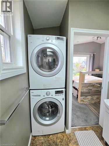 Studio laundry area featuring stacked front-load appliances and a folding shelf, inside the bathroom - 16 Forest Hill Road, St. Catharines, ON - Indoor Photo Showing Laundry Room