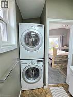 Studio laundry area featuring stacked front-load appliances and a folding shelf, inside the bathroom - 