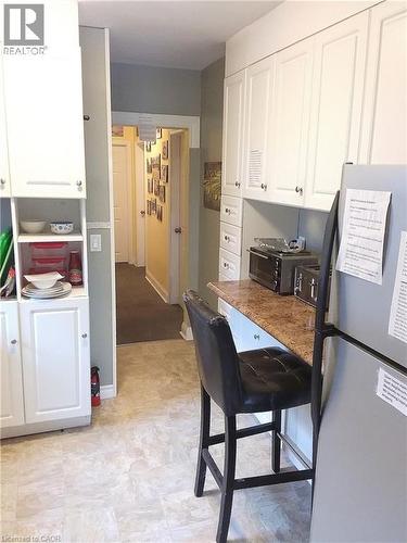 Main floor kitchen featuring extensive white cabinetry, a built-in breakfast bar with a speckled countertop, and light-toned tile flooring - 16 Forest Hill Road, St. Catharines, ON - Indoor