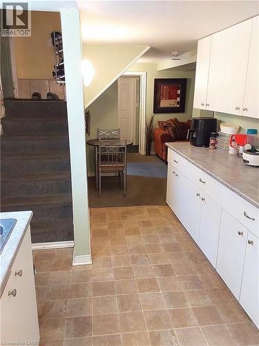 Basement kitchen area featuring extensive white cabinetry, light-toned countertop, and square tile flooring - 16 Forest Hill Road, St. Catharines, ON - Indoor Photo Showing Kitchen