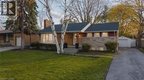 Exterior facade featuring stone and siding, a front lawn, mature trees, and a detached garage - 120 Elgin Crescent, Waterloo, ON - Outdoor With Facade