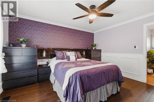 Bedroom featuring hardwood flooring, a ceiling fan with integrated lighting, decorative wainscoting, crown molding, and a patterned accent wall - 120 Elgin Crescent, Waterloo, ON - Indoor Photo Showing Bedroom