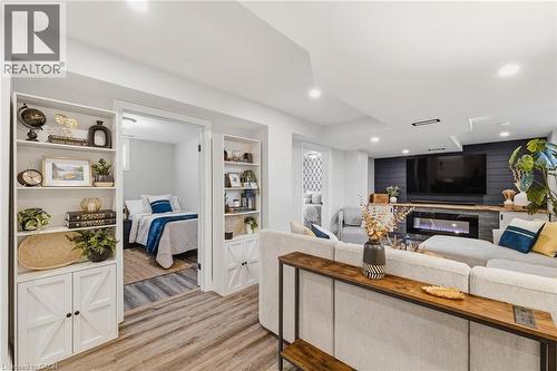 Open concept living space featuring wood-finish flooring, a built-in electric fireplace with a stone surround, and an accent wall with shiplap paneling - 120 Elgin Crescent, Waterloo, ON - Indoor With Fireplace