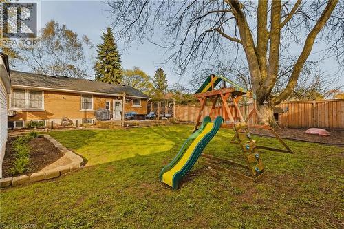 Expansive backyard featuring a manicured lawn, a large mature tree, and a wooden privacy fence - 120 Elgin Crescent, Waterloo, ON - Outdoor With Deck Patio Veranda