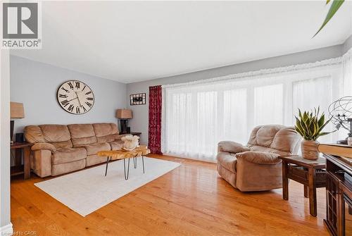 Living area with wood-finish flooring, light gray wall paint, and a bright window wall - 120 Elgin Crescent, Waterloo, ON - Indoor Photo Showing Living Room