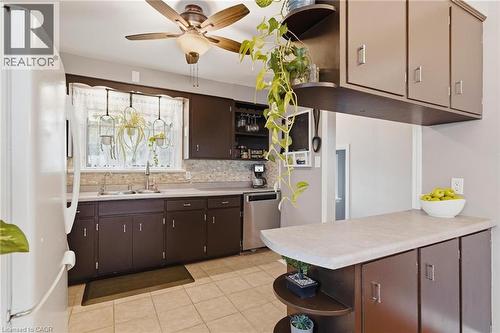 Kitchen with brown cabinetry, light-toned countertops, and a tiled backsplash - 120 Elgin Crescent, Waterloo, ON - Indoor Photo Showing Kitchen