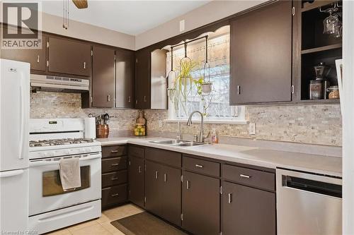 Kitchen featuring brown cabinetry, light-toned countertops, and a tiled backsplash - 120 Elgin Crescent, Waterloo, ON - Indoor Photo Showing Kitchen With Double Sink