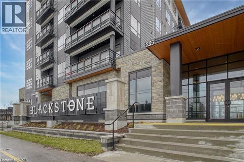 Contemporary multi-story building featuring a stone facade and balconies with glass railings - 251 Northfield Drive E Unit# 406, Waterloo, ON - Outdoor