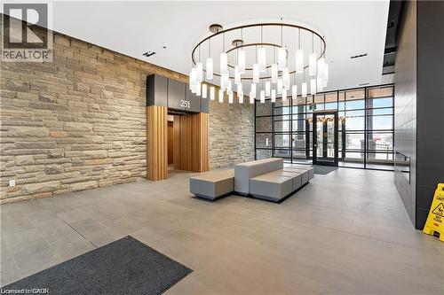 Spacious lobby featuring a stone accent wall, large format floor tiling, and a contemporary chandelier - 251 Northfield Drive E Unit# 406, Waterloo, ON - Indoor Photo Showing Other Room