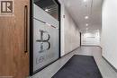 Frosted glass partition with ""Lounge"" branding, wood-finish door with a long black pull handle, concrete accent wall, recessed ceiling lighting, and grey tile flooring - 251 Northfield Drive E Unit# 406, Waterloo, ON  - Indoor Photo Showing Other Room 