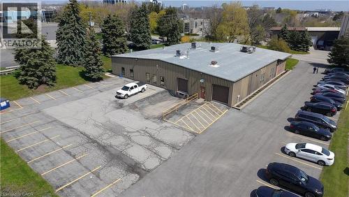 Industrial building featuring two garage bay doors, multiple windows, and a surrounding paved parking lot - 920 Sheldon Court, Burlington, ON 