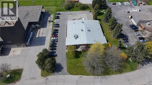 Industrial property featuring a central building with a metal roof, extensive paved parking areas, and surrounding green spaces with mature trees - 920 Sheldon Court, Burlington, ON 