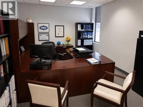 Spacious office featuring a wood-finish desk with an integrated hutch, built-in shelving, a large window with a roller shade, and ceiling-mounted fluorescent lighting - 920 Sheldon Court, Burlington, ON 