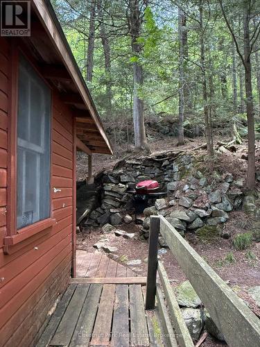 West side of cottage, bbq area built into the hill - Apl1136E - 19 Cache Lake, South Algonquin, ON - Outdoor With Deck Patio Veranda