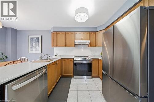Galley kitchen featuring light wood cabinetry, light-toned countertops, and stainless steel appliances including a refrigerator, range, and dishwasher - 200 Morrison Drive, Caledonia, ON - Indoor Photo Showing Kitchen