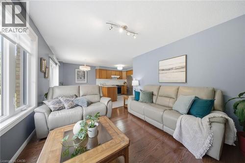 Open-concept living area with wood-finish flooring, abundant natural light from multiple windows, and a recessed kitchen beyond - 200 Morrison Drive, Caledonia, ON - Indoor Photo Showing Living Room