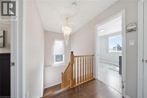 Hallway with wood-finish flooring, a tiered crystal chandelier, and a wood baluster staircase - 200 Morrison Drive, Caledonia, ON - Indoor Photo Showing Other Room