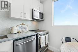 Kitchen featuring white cabinetry, a stainless steel microwave, a stainless steel dishwasher, a stainless steel range, and a light-toned countertop - 