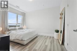 Light-filled interior featuring a full-height window, light wood-finish flooring, white baseboards, and a white interior door - 