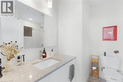 Bathroom featuring a white vanity with an integrated sink, a rectangular mirror, and a toilet - 