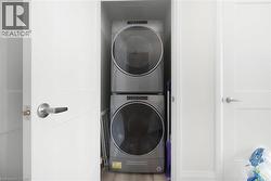 Dedicated laundry closet featuring a stacked washer and dryer unit - 