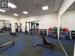 Fitness center featuring full-height wall mirrors, recessed lighting, and a durable rubber tile floor in a checkerboard pattern - 