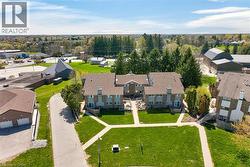 Multi-unit residential structure featuring brick and siding exteriors, individual patios, and a gravel driveway - 