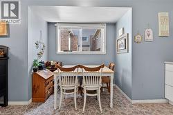 Recessed dining area featuring patterned flooring, light blue walls, a window with horizontal blinds, and white trim - 