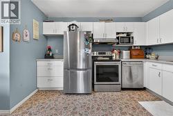 Kitchen featuring white cabinetry, stainless steel appliances, a built-in microwave, and stone-look flooring - 
