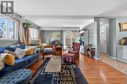 Inviting living area featuring hardwood flooring, multiple windows providing natural light, and a sliding glass door leading to an outdoor space - 