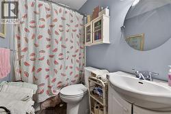 Bathroom featuring a white pedestal toilet, a white wall-mounted sink with a chrome faucet, and a circular wall mirror - 