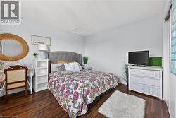 Bedroom featuring wood-finish flooring, light blue walls, and a recessed ceiling panel - 