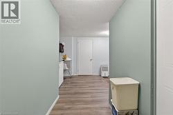 Hallway with wood-finish flooring, light blue walls, and a white paneled door - 