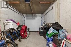 Single-bay garage featuring concrete walls and flooring, an overhead garage door, and visible garage door opener mechanism - 