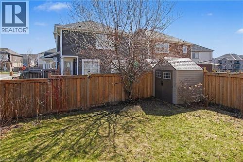 Expansive backyard featuring a manicured lawn, wood fencing, and a detached storage shed with a shingle roof - 60 Postmaster Drive, Kitchener, ON - Outdoor