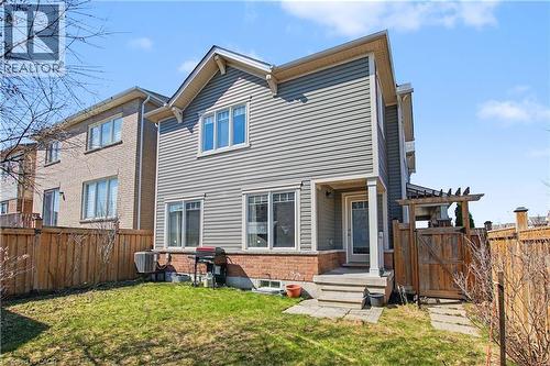 Rear exterior featuring gray siding, brick foundation, and multiple windows - 60 Postmaster Drive, Kitchener, ON - Outdoor