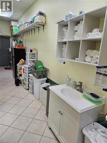 Utility space featuring tile flooring, a single vanity with an integrated sink, a wall-mounted shelving unit, and an additional wall shelf - 9688 Leslie Street Unit# 16, Richmond Hill, ON 