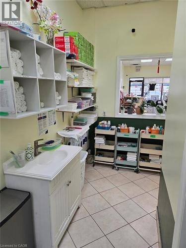 Utility area featuring a white vanity with an integrated sink, wall-mounted shelving, and square ceramic tile flooring - 9688 Leslie Street Unit# 16, Richmond Hill, ON 