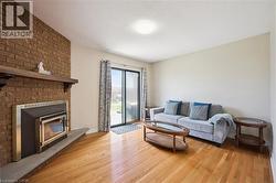 Living area featuring wood-finish flooring, a brick accent wall with a fireplace insert, a wood mantel, and sliding glass doors providing outdoor access - 