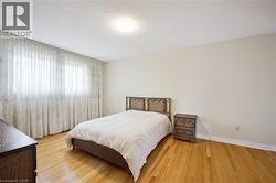 Hardwood flooring spans this bedroom with an overhead flush-mount light fixture - 